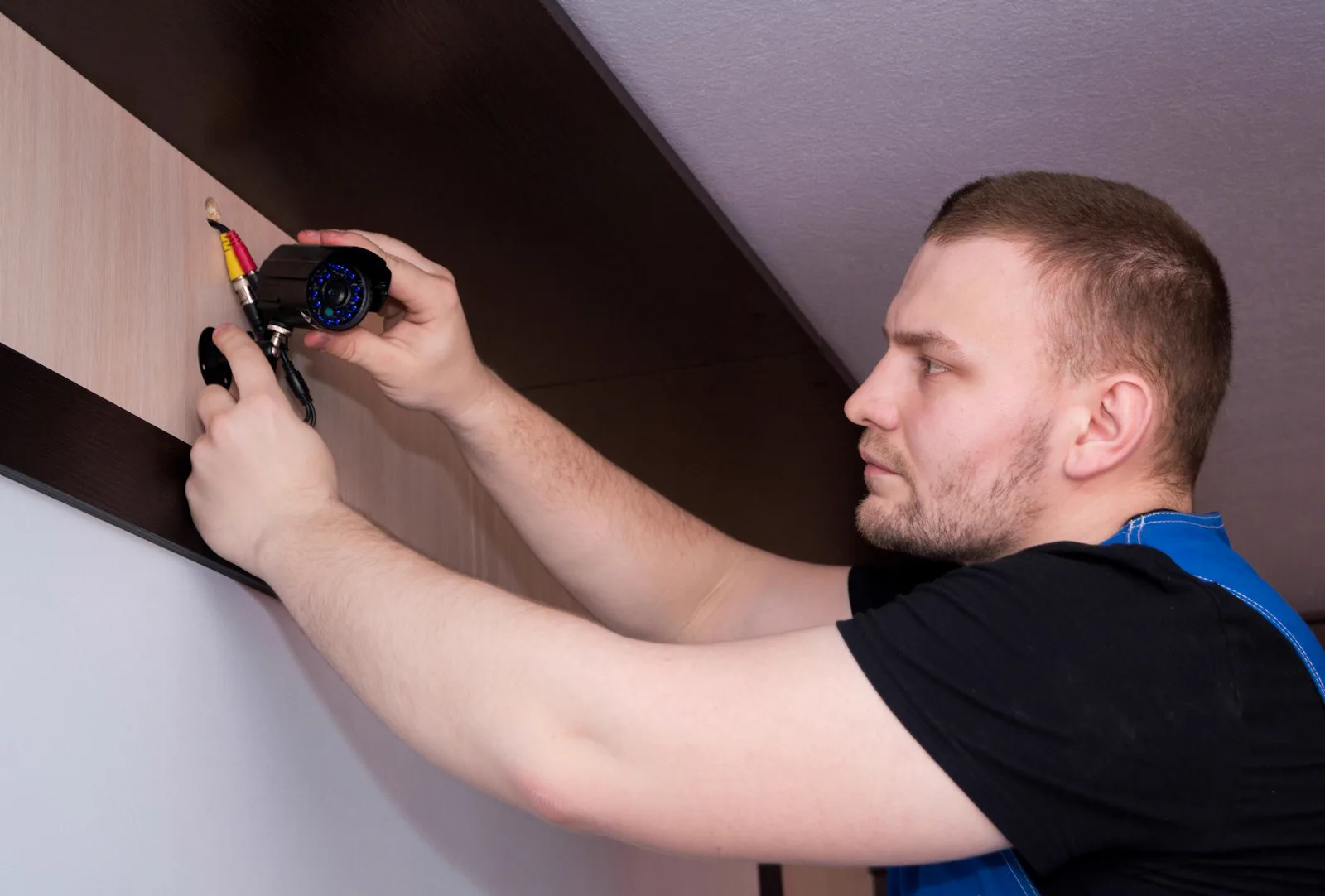 Technician installing a surveillance camera on a wall